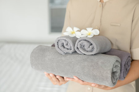 A hotel maid stacked towels on the bed and placed flowers on the towels in a hotel room.の写真素材