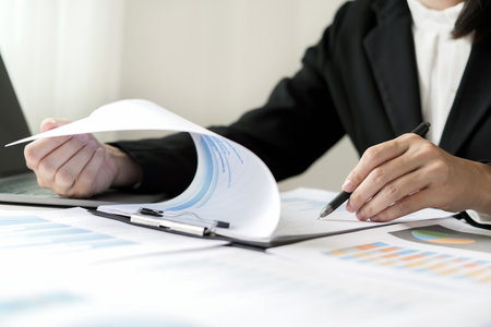 Asian businesswoman sit at their desks and calculate financial graphs showing results about their investments and plan successful business growth process.の写真素材