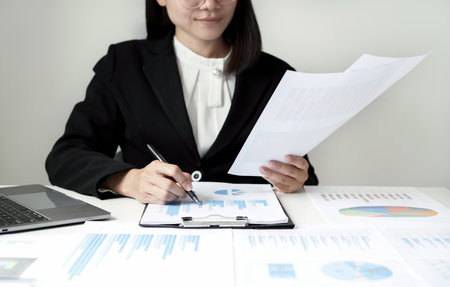 Asian businesswoman sit at their desks and calculate financial graphs showing results about their investments and plan successful business growth process.の写真素材