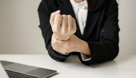 Woman hand with wrist pain numbness and pain in the palm of the hand has pain and tingling in the nerve endings This is a side effect of sitting and working for a long time on a laptop at the office.の写真素材