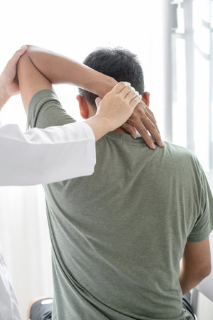 Female physiotherapists provide physical assistance to male patients with shoulder injuries massaging their shoulders for muscle recovery in the rehabilitation center. Physiotherapy concepts.の写真素材