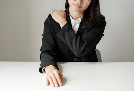 Asian female accountant is tired from working in a chair have Shoulder pain, stretching to relax and relax while working hard at the office.の写真素材
