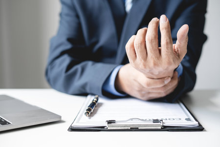 man hand with wrist pain numbness and pain in the palm of the hand has pain and tingling in the nerve endings This is a side effect of sitting and working for a long time on a laptop at the office.の写真素材