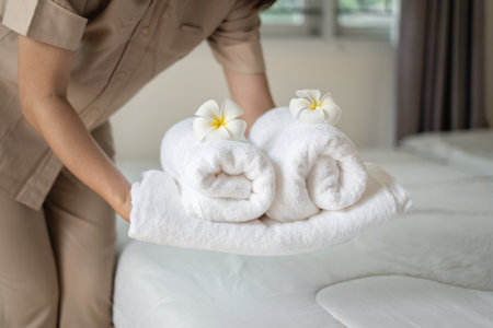 A hotel maid stacked towels on the bed and placed flowers on the towels in a hotel room.の写真素材