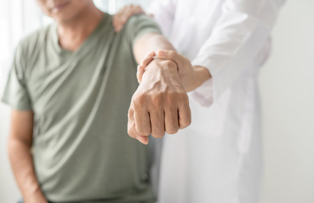 Female physiotherapists provide physical assistance to male patients with shoulder injuries massaging their shoulders for muscle recovery in the rehabilitation center. Physiotherapy concepts.の写真素材