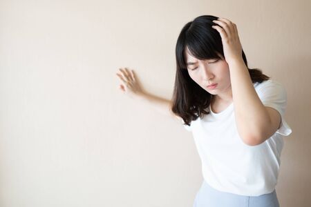 Young asian female suffering from dizziness, vertigo and headache over white background. Cause of dizzy inclued migraine, stress, stroke, BPPV, Meniereâ€™s disease or brain tumor. Health care problem.の素材 [FY310149077198]