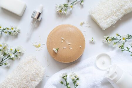 Natural soap bars w/ essential oil dropper, organic herbal, cosmetic tube, loofah and towel on white...