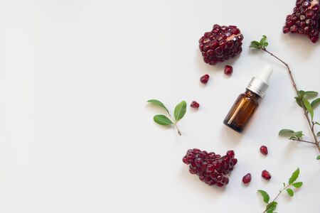 Serum bottle containing organic pomegranate seed oil extract on white background. Cosmetic natural serum, skincare, essential oil products. Beauty product branding mock-up. Flat lay. Copy space.の写真素材