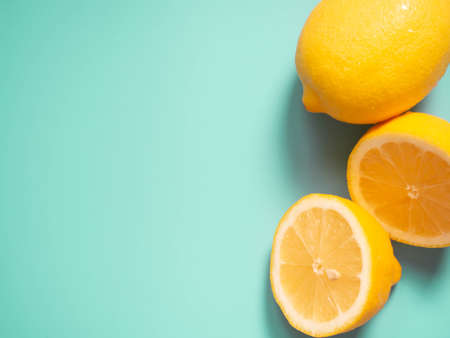 Fresh yellow lemon citrus fruit on lime green background. Cut half and whole lemons. Copy space. Top view.の写真素材