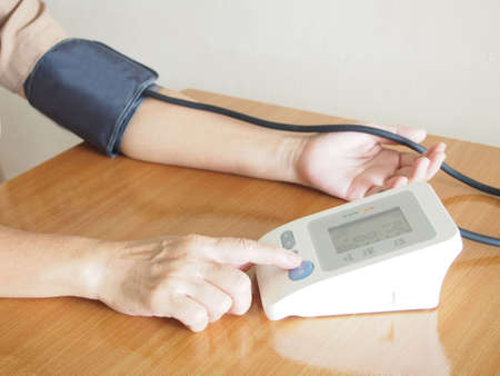 Middle aged women measuring her blood pressure and heart rate with automatic blood pressure monitor...