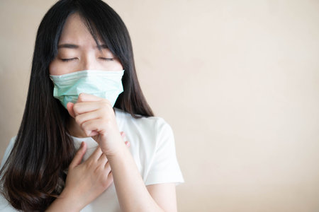 Young ill woman have a cough and wearing protective mask. Medical face masks protecting from cold, flu or other virus. Health care concept. Copy space.の写真素材