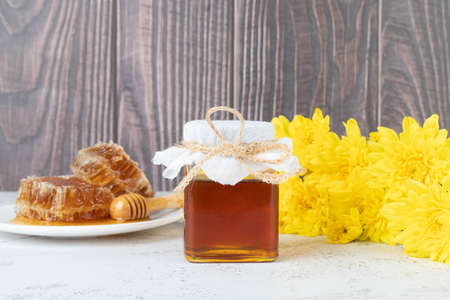 Fresh honey bottle with organic honeycomb and wild flower on wooden table. Healthy food concept.の写真素材