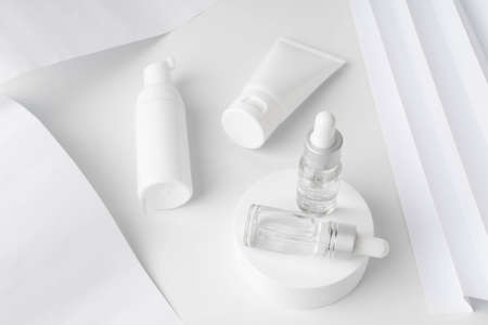 Beauty natural skincare product mock up. Serum glass vials on white circle podium with lotion bottle and facial foam tube.の写真素材