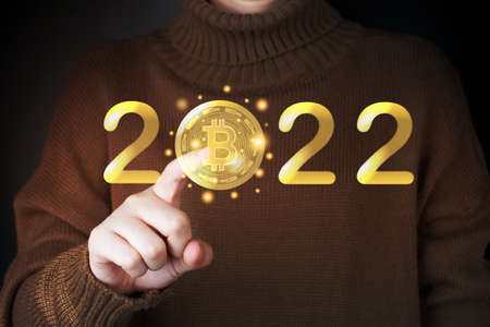 Future of digital cryptocurrency block chain market in 2022 concept. Smart investor pointing bitcoin symbol with 2022 golden number.の写真素材