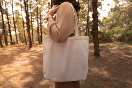 Blank white tote bag canvas fabric with handle mock up design. Close up of woman holding eco or...