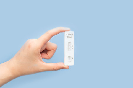 Woman hands holding SARS CoV-2 Rapid Antigen Test kit (ATK) with positive result during swab testing...