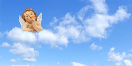 Thinker angel above the clouds on a blue sky background: greeting card for christmas, baptism or communion.の写真素材
