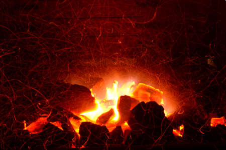 Embers of coal burning. Orange flames blaze in the fire. Bright orange grid nature brand. Burning...