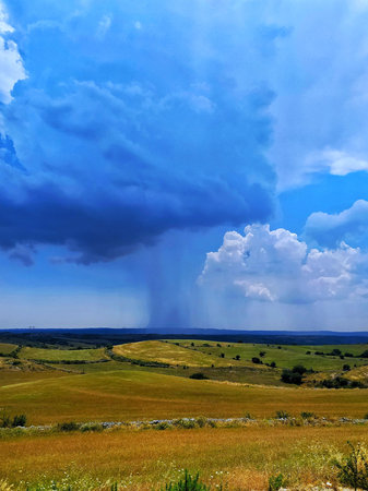 Storm Clouds and a Curtain of Rain on a Countryside Landscape with Hills.