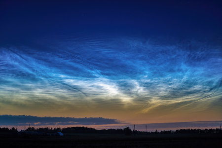 A stunning display of noctilucent clouds shimmering in the twilight sky above a serene natural landscape.の写真素材