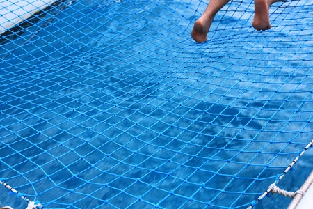 Human feet over the net and water on catamaranの写真素材