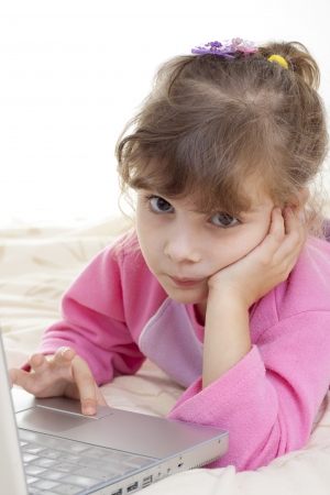 little girl playing on a laptop bored of itの写真素材