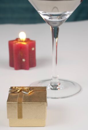 romantic proposal theme with a golden ring box a shampain glass and a red candle with flameの写真素材