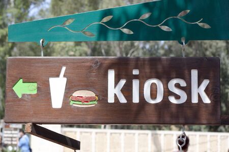 a wood sign with a green arrow with a hamburger and kioskの写真素材