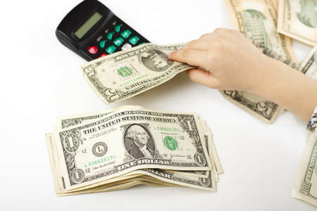 hand separating dollars by type on white background and a black calculatorの写真素材