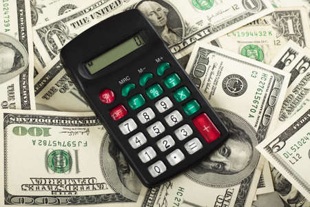 a small black calculator on a pile of dollar bills