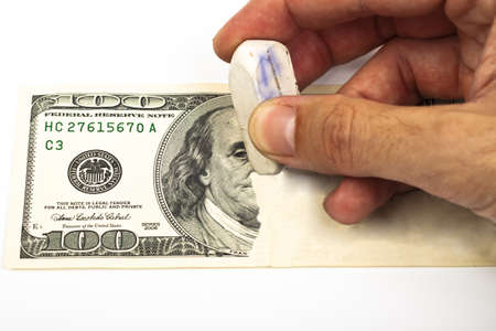 erasing a 100 dollar bill with a white eraserの写真素材