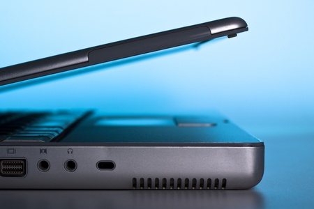 silver laptop side view lid open with blue background light
