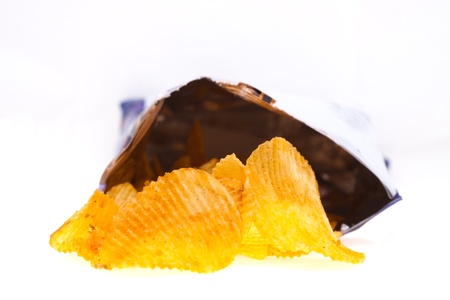 spiced golden chips pile with the bag on white backgroundの写真素材