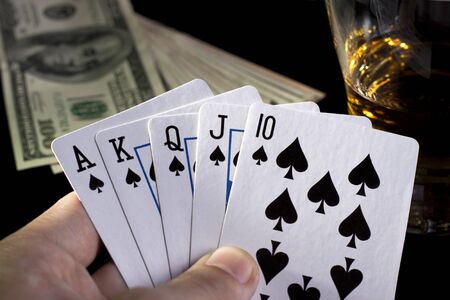 poker playing cards whiskey and some money on a table with reflectionの写真素材