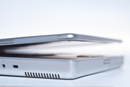 silver laptop sideview fading out on white laptop closing lidの写真素材