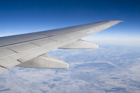 airplane wing in the air trough the window with terestrial view and blue skyの写真素材
