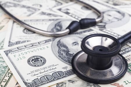 Black stethoscope close-up on top of Dollar banknotes side viewの写真素材