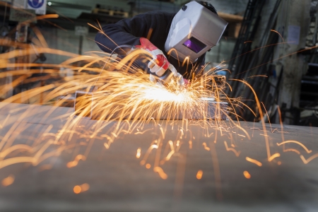 Metal wroker in a factory grinding with sparksの写真素材