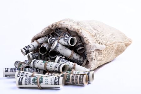 Dollars rolled up with rubber band in Sack brown isolated on white backgroundの写真素材