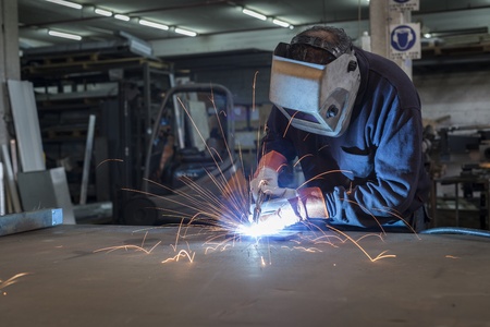 Welder working in a steel factory with sparks flyig 