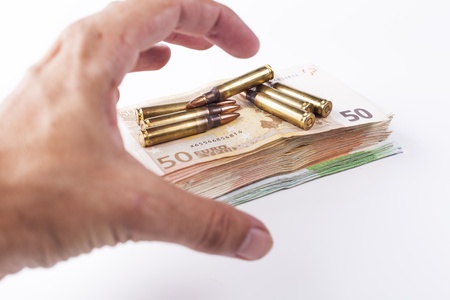 Hand grabbing a pil of bullets with euro banknotes isolated on white backgroundの写真素材