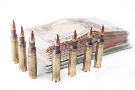 Multiple rifle bullets guarding a apile of  euro banknotes isolated on whiteの写真素材