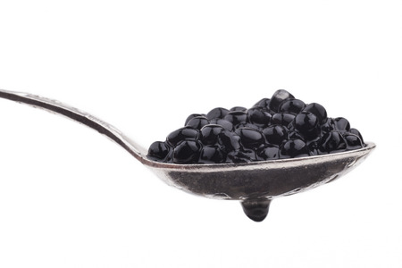 Black caviar beads on silver spoon close-up isolated on white の写真素材