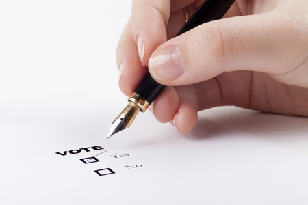 Woman hand voting yes in check-box with blue fountain pen in the airの写真素材