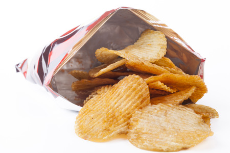 Potato ships pouring out of bag isolated on white backgroundの写真素材