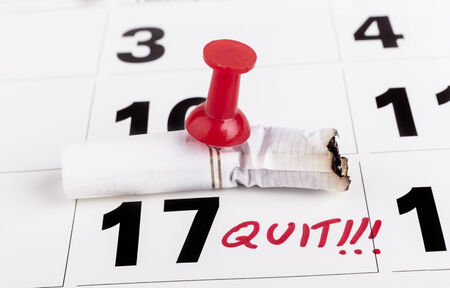 Quit smoking deadline with cifarette butts nailed with red pin to calendarの写真素材