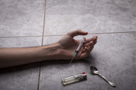 Drug Addict hand with syringe on the floor with a bag of drugs a spoon and a lighterの写真素材