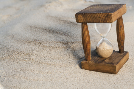 Vintage hourglass in the sand with small shadowの写真素材
