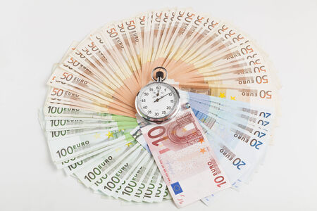Circle made of euro banknotes with silver analog stopwatch in the middleの写真素材