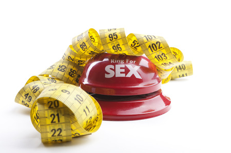 Red Ring for sex bell close-up with yellow measuring tape  isolated on white backgroundの写真素材